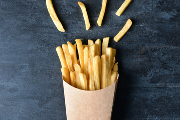 Paper box with tasty french fries on black background, closeup