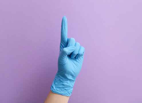 Woman In Medical Glove Pointing At Something On Violet Background