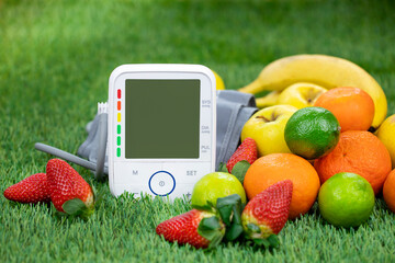 Blood pressure monitor and fresh fruits on a green lawn. Healthy lifestyle and prevention of hypertension concept