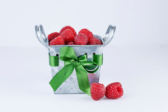 Raspberries In Metallic Basket With Green Ribbon On White Background