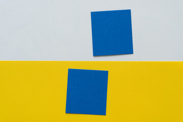 two blue paper squares on white and yellow