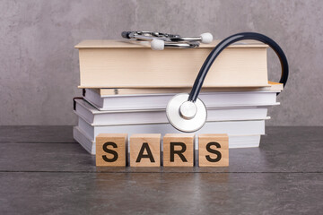 wooden block form the word SARS with stethoscope on the doctor's desktop. medical concept. concept of medical education with book and stethoscope