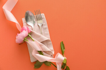Stylish cutlery with flowers on coral background
