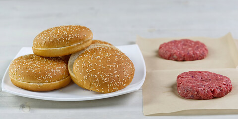 cheeseburger and beefburger ingredients. bun and raw burger cutlets. Burger bbq party. close up