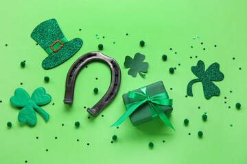 Horseshoe with gift and decor on color background. St. Patrick's Day celebration