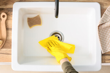 Woman wiping ceramic sink, closeup
