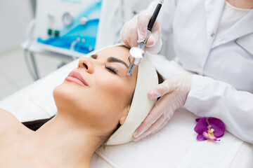 close-up view of a woman's head receiving diamond microdermabrasion treatment. skin care and...