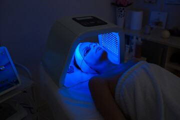 Woman having Ultraviolet LED light facial treatment at beauty salon. Cosmetology. female Face At...