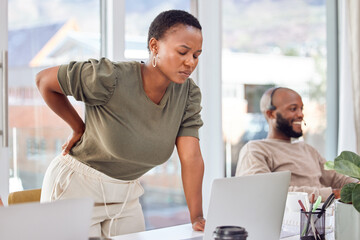 Could it be my chair or something else.... Shot of a businesswoman experiencing back pain while getting up from her desk.
