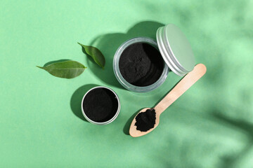 Jar with activated charcoal tooth powder on green background