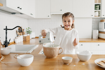 Adorable girl preparing icing pancakes at the kitchen. Concept of food preparation. Casual lifestyle photo series in real life interior