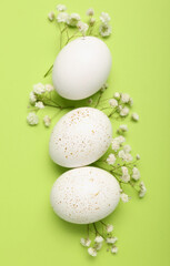 Composition with beautiful Easter eggs and gypsophila flowers on green background