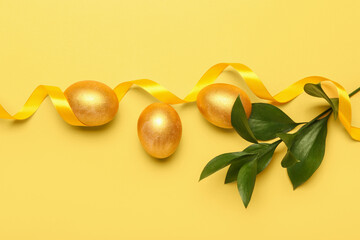 Golden Easter eggs, plant branch and ribbon on color background