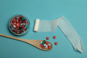 Studio photo of a spoonful of pills on a blue background. The pills have different colours. There...