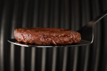 Veggie plant-based meat cutlet on barbecue grilling tool - spatula handle. Soybean fake patty, gluten free, non-meat vegetarian and vegan food concept.