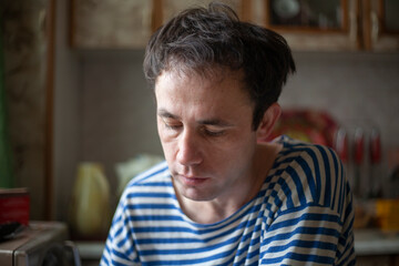 Obraz premium The guy in the vest. A man sits in the kitchen in the morning. The young man stayed at home.