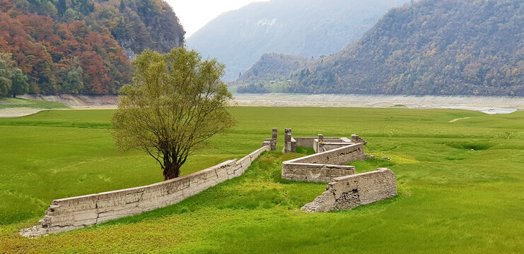 Landscape of Lake Corlo against the background of ruins and a green meadow. Panorama.