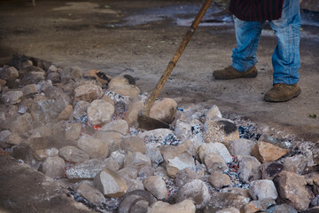 Gaucho with stones heating in a well to cook curanto. Shovel, fire, smoke and rocks. Typical food of the Argentine Patagonia.