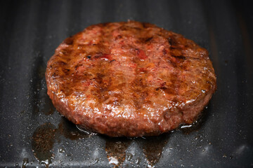 Process of roasting veggie plant-based meat cutlet on barbecue grill plate. Soybean fake patty, gluten free, non-meat vegetarian and vegan food concept. Raw for burger. Close-up photo.