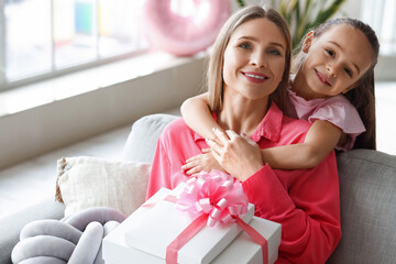 Little girl hugging her mother with gift at home on International Women's Day