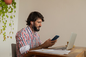 Young business man working at home with laptop and papers on desk. Home office concept.