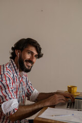 Young business man working at home with laptop on a brown arm chair. Home office concept.