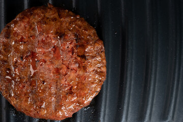 Process of roasting meat steak on barbecue grill plate. Cooking beef or pork patty. Raw cutlet for burger. Close-up photo.