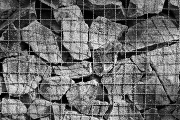many large stones behind a metal mesh, background, texture, photograph taken in black and white. 