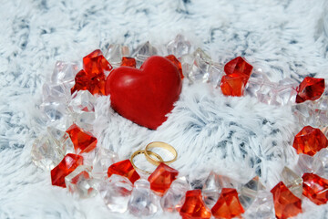 Red heart and golden rings on a soft and fluffy plaid. The color scheme is white, red. Valentine's day, February 14, lovers