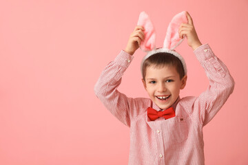 Funny little boy with bunny ears on pink background