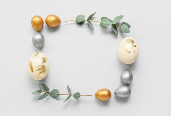 Frame made of Easter eggs and eucalyptus branches on light background