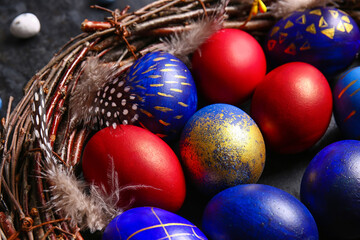 Nest with stylish Easter eggs on dark background