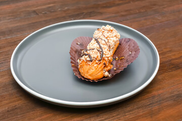 Fresh baked sweet creamy eclair dessert on plate kitchen wooden table, sugar food, utensils...