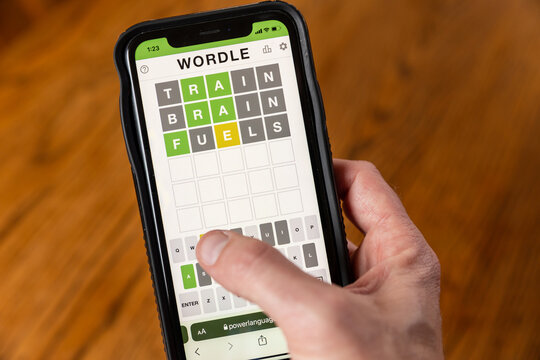 Hands playing Wordle game on phone.