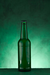 Bottle of beer for St. Patrick's Day celebration on green background