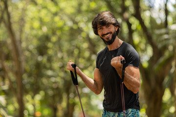 Strong man guy working out with elastic rubber bands at a park outdoors. Athlete male person during workout with additional sport equipment. High quality photo