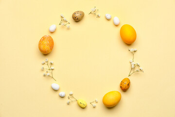 Frame made of Easter eggs and flowers on beige background