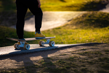 Legs in yellow sneakers on a skateboard at the skate park in the evening in rays of sunlight