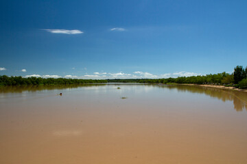 Panorama view of the brown water Parana river under a clear blue sky. View of the wide river and jungle reflection in the water.