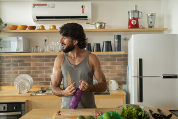 Happy and healthy young man meal prepping whole vegetarian meal in the kitchen. High quality photo