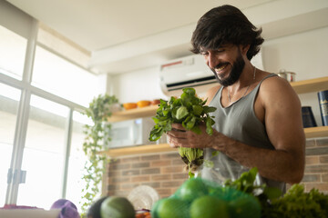 Happy and healthy young man meal prepping whole vegetarian meal in the kitchen. High quality photo