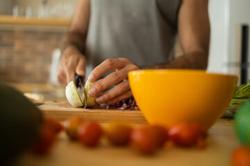 Happy and healthy young man meal prepping whole vegetarian meal in the kitchen. High quality photo