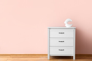 Stylish decor on modern chest of drawers near color wall