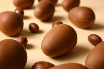 Different chocolate Easter eggs on beige background, closeup