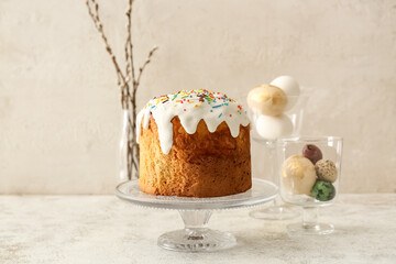 Dessert stand with delicious Easter cake and eggs on light background