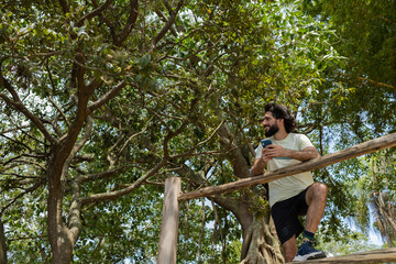 Young man at a park on a beautiful sunny day with mobile phone.