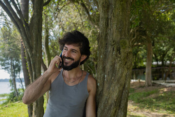 Young man at a park on a beautiful sunny day with mobile phone.