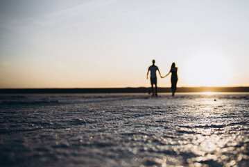 Fototapeta premium couple walking on the beach at sunset love sun man woman sunset 