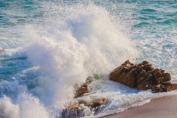 Gros plan d'une vague qui se déchaine sur des rochers