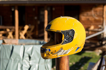 Yellow broken motorcycle helmet attached to a wooden stake outdoor. Close up, selective focus
